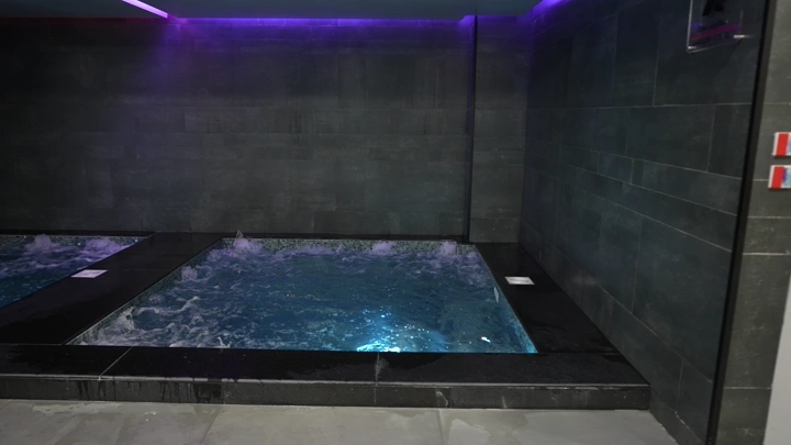جاكوزي في غرفة السباحة بإضاءة منخفضة، لقطة داخلية.
