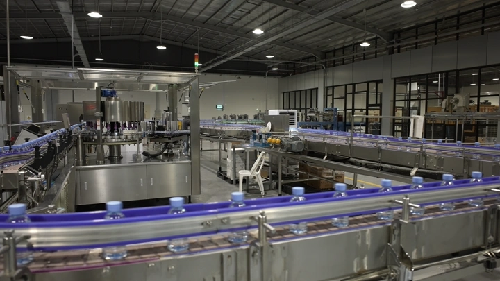 خط إنتاج زجاجات المياه في مصنع حديث، لقطة داخلية.