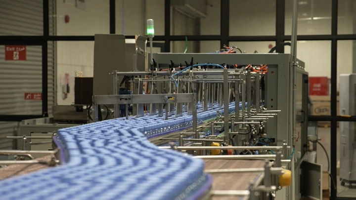 خط إنتاج زجاجات مياه في مصنع، لقطة داخلية.