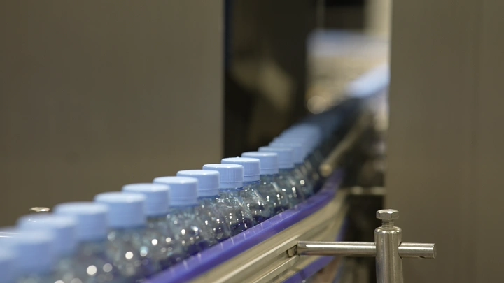 زجاجات مياه على خط إنتاج في مصنع، لقطة مقربة.