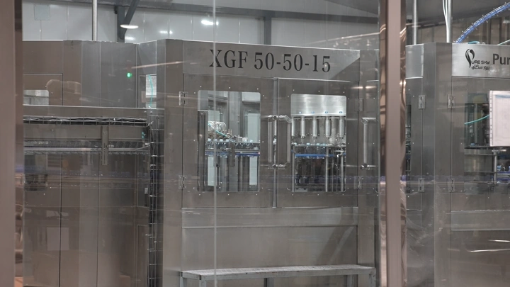 آلة تعبئة زجاجات في مصنع مياه، لقطة داخلية.