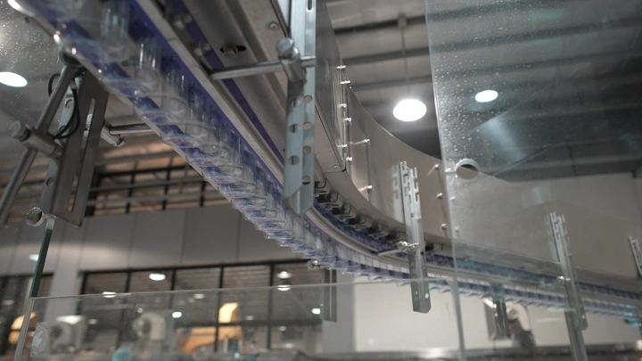خط إنتاج زجاجات مياه في مصنع، لقطة داخلية.