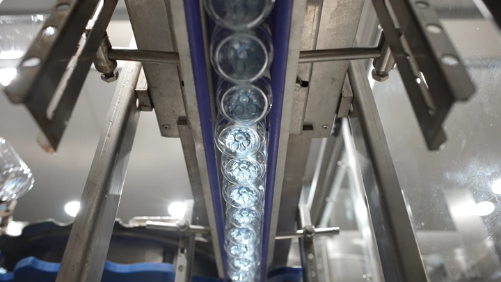 زجاجات مياه على خط إنتاج في مصنع، لقطة من الأسفل.