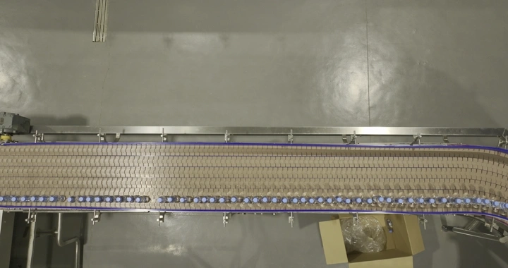 خط إنتاج زجاجات مياه في مصنع، لقطة علوية.