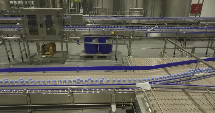 خط إنتاج زجاجات مياه في مصنع، لقطة داخلية.