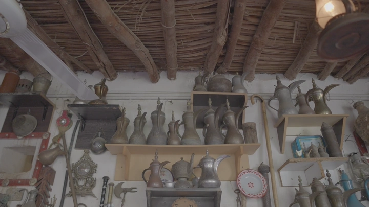 مجموعة من الدلال والتحف الأثرية على رفوف خشبية في متحف، لقطة داخلية.