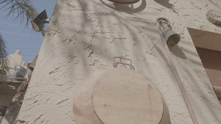 جدار بيت طيني مع أدوات تقليدية معلقة، لقطة نهارية.