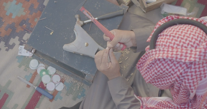 حرفي يصنع مدخنة يدوية على سجادة ملونة، لقطة علوية.