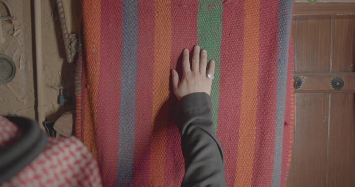 يد تلمس خيوط السدو الملونة في غرفة تقليدية، لقطة قريبة.