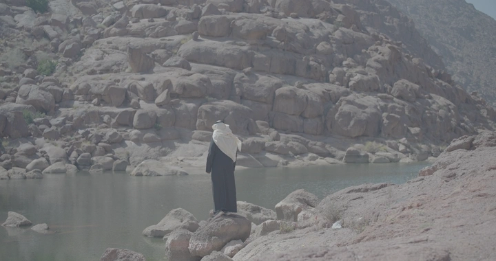 رجل يرتدي الزي التقليدي يقف أمام بحيرة في جبال الكشرية، لقطة طبيعية.