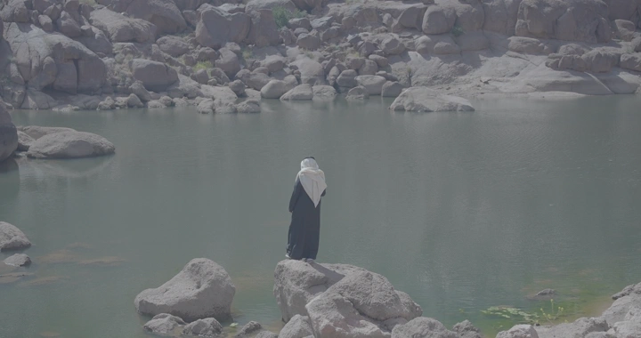 شخص يقف بجانب بحيرة في جبال الكشرية، لقطة نهارية.