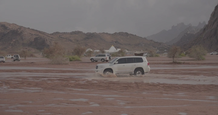 سيارة تسير في أرض مغمورة بالمياه بعد الأمطار في حائل، لقطة طبيعية.