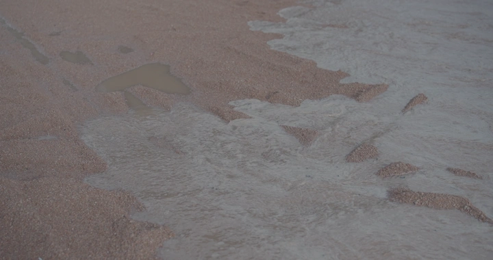 مياه الأمطار تتدفق على أرض رملية في حائل، لقطة قريبة.