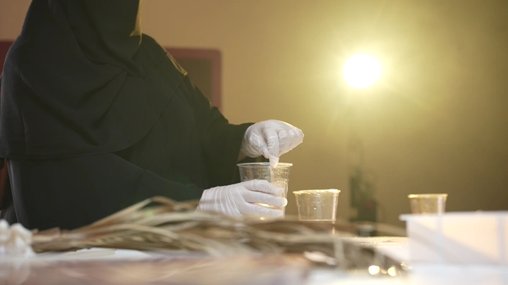 امرأة تخلط الريزن في كوب بلاستيكي، إضاءة خلفية.