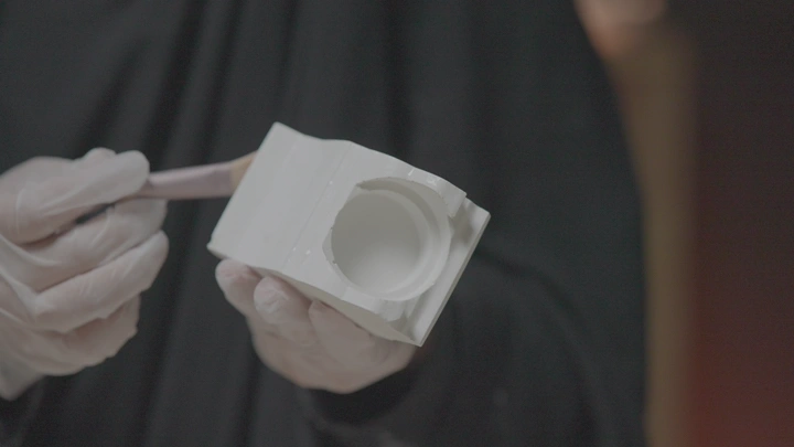 حرفة صب وتشكيل و يد ترتدي قفازًا تمسك قالب جبس، لقطة مقربة.