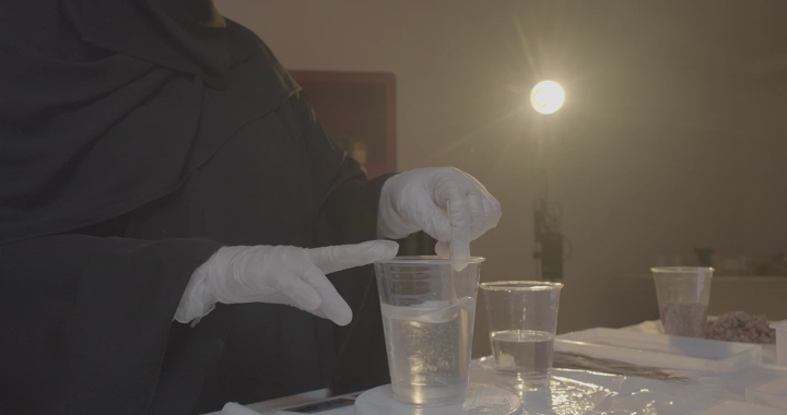 حرفة صنع تحف من الريزن و يرتدي قفازات يخلط الريزن في استوديو مضاء، لقطة قريبة.