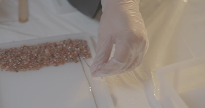 يد ترتدي قفاز تعمل على تحف من الريزن، لقطة قريبة.