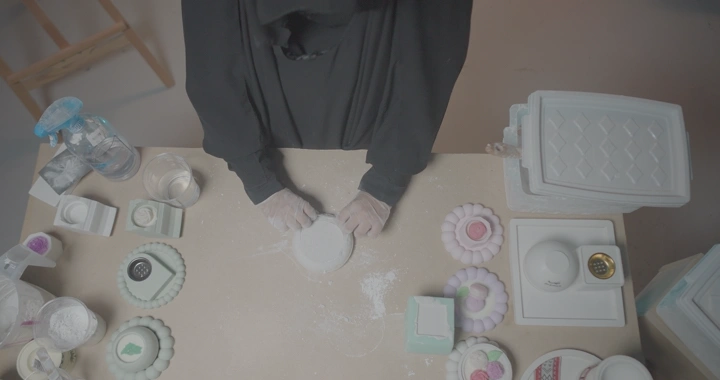 حرفة صب وتشكيل الجبس مع امرأة تصب الجبس في قوالب على طاولة، لقطة علوية.