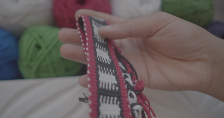 يد تمسك سدو مصنوع يدوياً مع خيوط ملونة، لقطة مقربة.