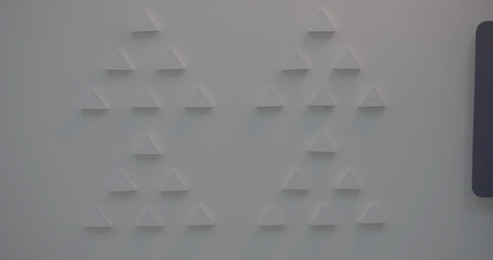 تشكيل مثلثات بيضاء على جدار رمادي، لقطة قريبة.