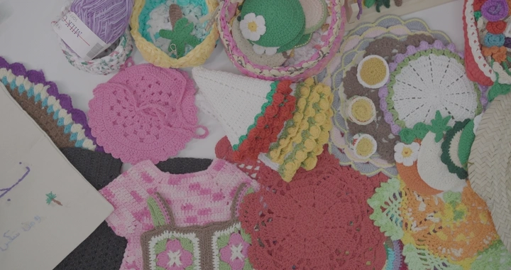 مجموعة من مشغولات الكروشيه الملونة على طاولة، لقطة علوية.