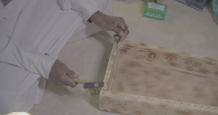 نجار يعمل على صندوق خشبي في ورشة، لقطة قريبة.