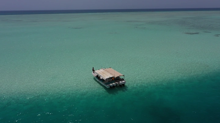 قارب في مياه زرقاء صافية في أملج، لقطة جوية.