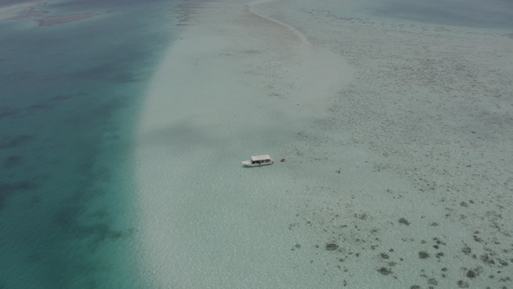 قارب في مياه زرقاء صافية في أملج، لقطة جوية.