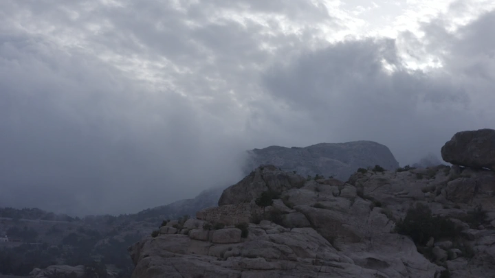 جبال صخرية في النماص تحت سماء غائمة، لقطة طبيعية.