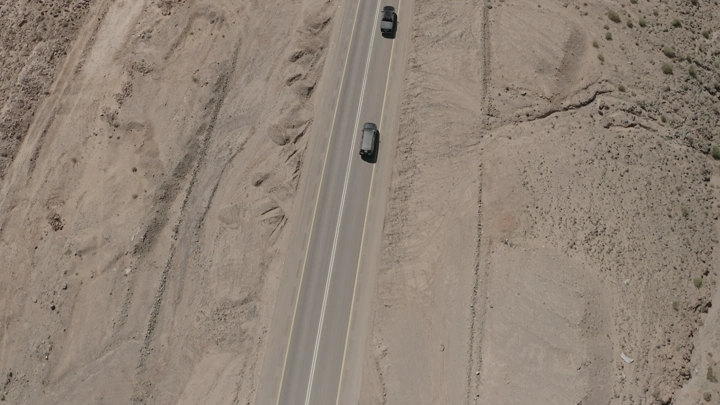 طريق صحراوي مع سيارتين يعبران من تبوك لنيوم، تصوير جوي.