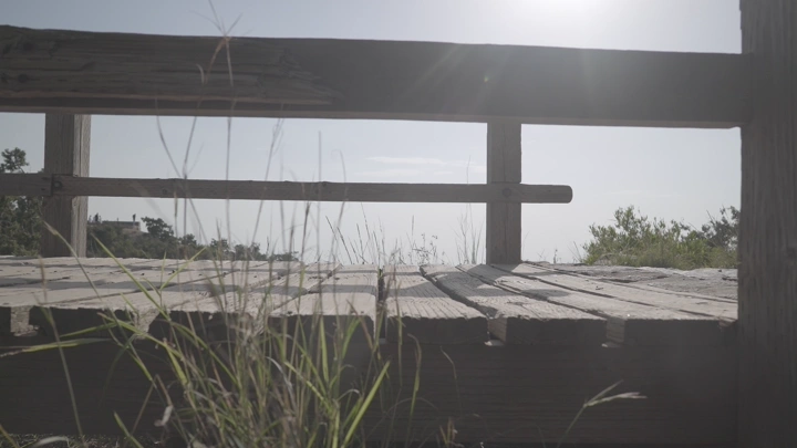 جسر خشبي في الطبيعة تحت أشعة الشمس يعبر عليه رجل، لقطة منخفضة.