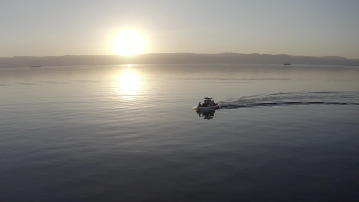 قارب صغير في البحر عند غروب الشمس في محافظة حقل، لقطة جوية.