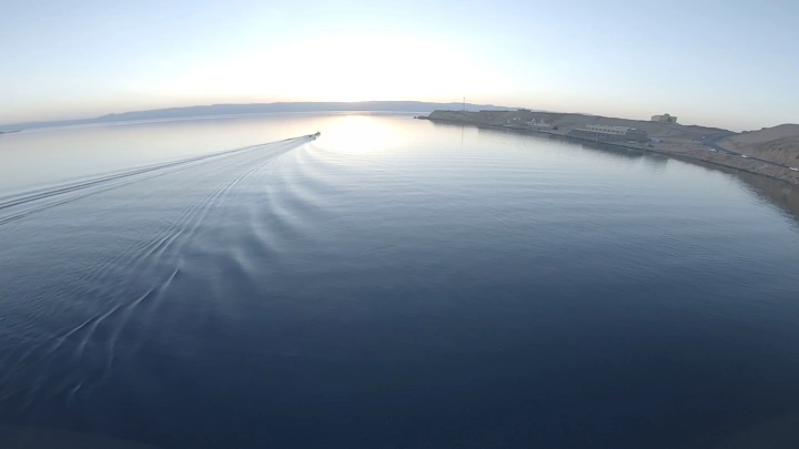 قارب في مياه هادئة عند غروب الشمس في محافظة حقل، لقطة جوية.