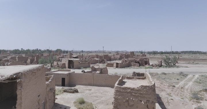 مبانٍ طينية قديمة في رياض الخبراء تحت سماء زرقاء، لقطة جوية.