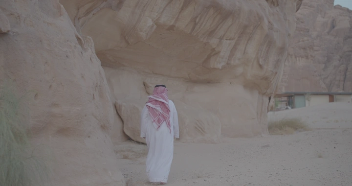 رجل يرتدي الزي السعودي يمشي بين جبال العلا، لقطة طبيعية.