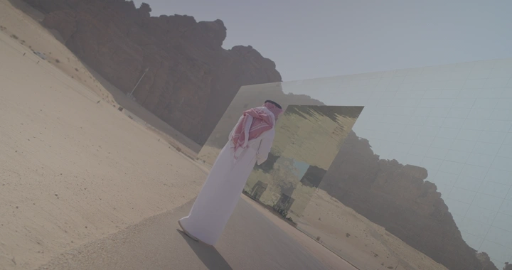 شخص يرتدي ثوبًا أمام قاعة مرايا في العلا، لقطة من الخلف.