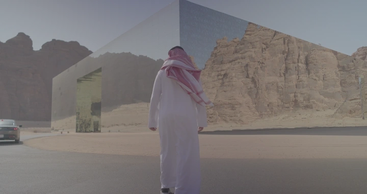 شخص يرتدي الزي السعودي أمام قاعة مرايا العلا، لقطة من الخلف.