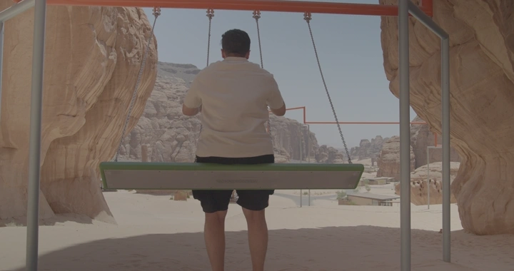 شخص يجلس على مرجيحة في جبال العلا، لقطة خلفية.