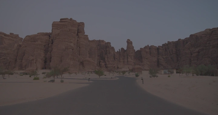 رجل يقود الدراجة بين جبال العلا في المساء، لقطة أرضية.