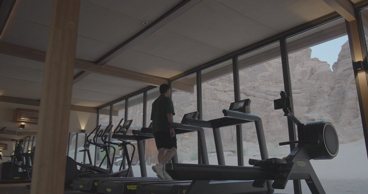رجل يمشي على جهاز سير في صالة رياضية بالعلا، لقطة داخلية.