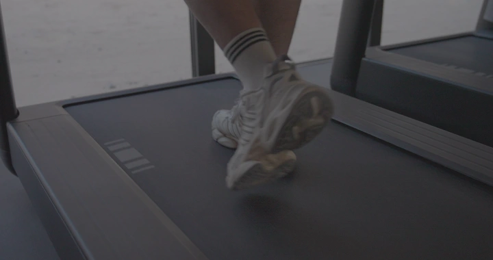 رجل يمشي على جهاز سير في صالة رياضية، لقطة مقربة.