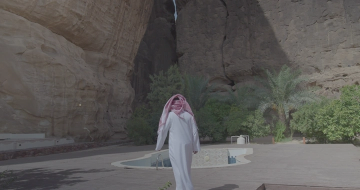 رجل يرتدي الزي السعودي يمشي في ساحة جبلية بالعلا، لقطة واسعة.