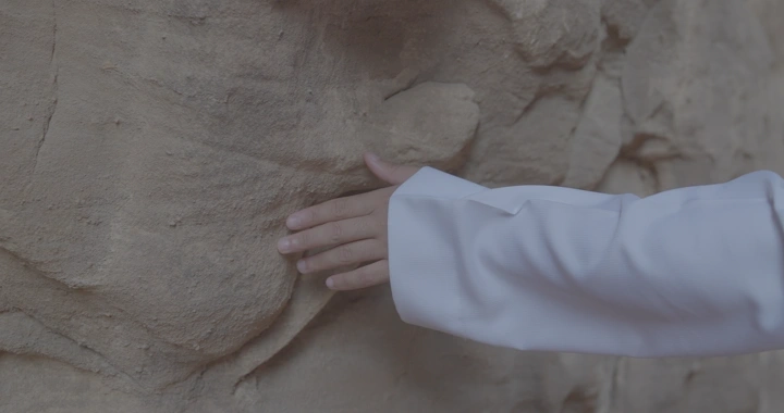 يد تلمس صخرة في جبال العلا، لقطة قريبة.