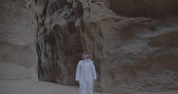 رجل يقف أمام صخور جبال العلا، لقطة واسعة.