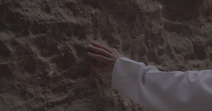 يد تلمس جدار صخري في جبال العلا، لقطة قريبة.