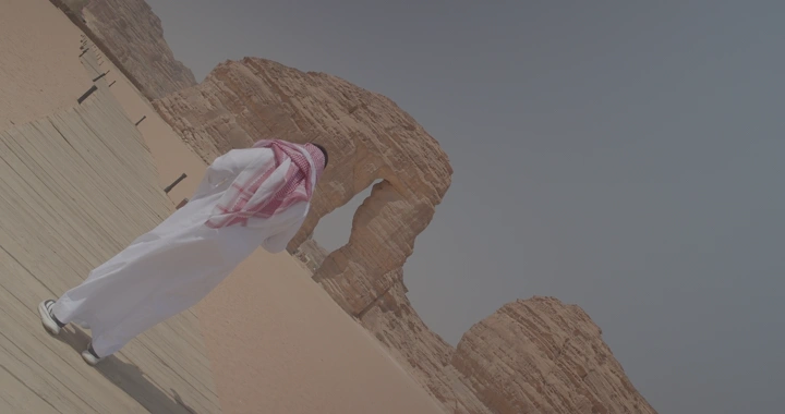 رجل يقف أمام جبل الفيل في العلا، لقطة من الخلف.