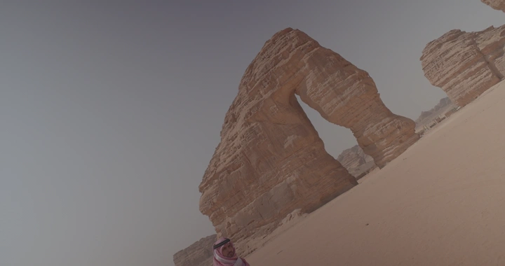 شخص يقف امام جبل الفيل في العلا، لقطة مائلة.