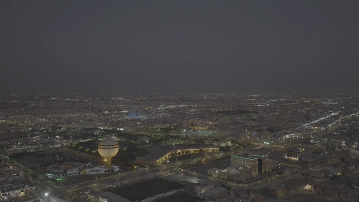 برج مياه بريدة ومركز الملك خالد الحضاري ومبنى أمانة المنطقة في القصيم، لقطة جوية في الليل.