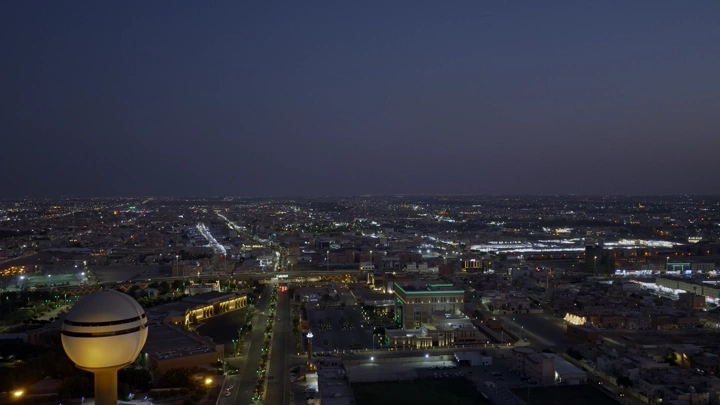 منظر جوي لمدينة بريدة ليلاً مع برج المياه مضاء.