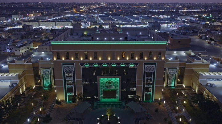 مبنى مضاء في مدينة القصيم ليلاً، لقطة جوية.